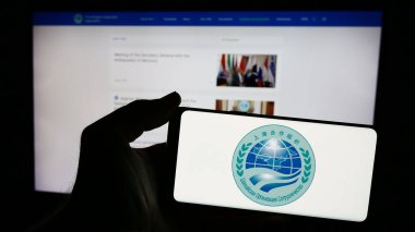 Stuttgart, Almanya - 06-24-2024: Web sayfası önünde Avrasya Şangay İşbirliği Örgütü (SCO) logosu olan cep telefonu sahibi kişi. Telefon ekranına odaklan.