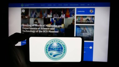 Stuttgart, Almanya - 06-24-2024: Web sayfası önünde Avrasya Şangay İşbirliği Örgütü (SCO) logosu bulunan kişi. Telefon ekranına odaklan.