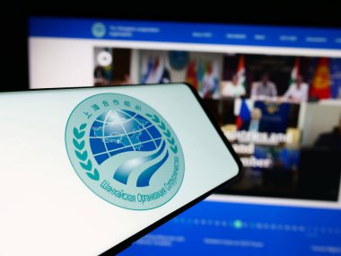 Stuttgart, Germany - 06-24-2024: Cellphone with logo of Eurasian Shanghai Cooperation Organisation (SCO) in front of website. Focus on center-left of phone display. clipart