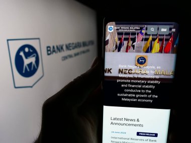 Stuttgart, Almanya - 06-24-2024: Logo önünde Malezya Merkez Bankası (BNM) internet sayfası bulunan kişi. Telefon ekranının merkezine odaklan.