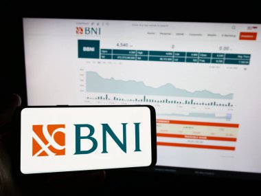 Stuttgart, Almanya - 06-24-2024: Endonezyalı finans şirketi Bank Negara Endonezya 'nın (BNI) logosuna sahip cep telefonu sahibi kişi web sayfası önünde. Telefon ekranına odaklan.