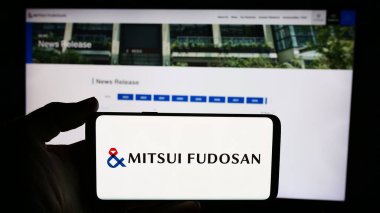 Stuttgart, Almanya - 06-24-2024: Japon emlak şirketi Mitsui Fudosan Co. Ltd. 'nin logosuyla cep telefonu tutan kişi iş sayfasının önünde. Telefon ekranına odaklan.