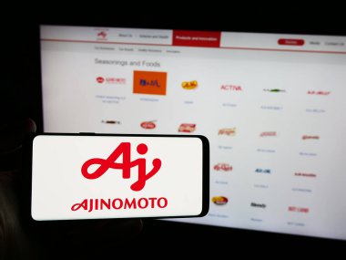 Stuttgart, Almanya - 06-24-2024: Japon gıda şirketi Ajinomoto Co. Inc. 'nin logosuna sahip akıllı telefon sahibi kişi web sitesinin önünde. Telefon ekranına odaklan.