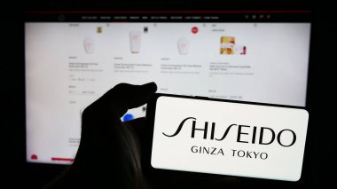 Stuttgart, Almanya - 06-24-2024: Japon kozmetik şirketi Shiseido Co. Ltd. 'nin logosuyla cep telefonu tutan kişi iş sayfasının önünde. Telefon ekranına odaklan.