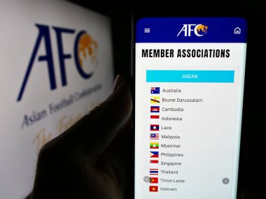 Stuttgart, Almanya - 06-25-2024: Logo önünde Asya Futbol Konfederasyonu (AFC) ortaklığı web sayfası ile cep telefonu tutan kişi. Telefon ekranının merkezine odaklan.