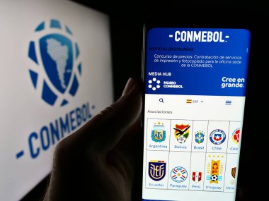 Stuttgart, Almanya - 06-25-2024: Logo önünde Konfederasyon Sudamericana de Futbol (CONMEBOL) web sitesi bulunan kişi. Telefon ekranının merkezine odaklan.