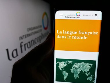 Stuttgart, Almanya - 06-26-2024: Uluslararası Örgüt Internationale de la Francophonie 'nin logo önündeki web sayfası ile cep telefonu tutan kişi. Telefon ekranının merkezine odaklan.