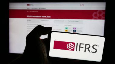 Stuttgart, Almanya - 06-26-2024: İnternet sayfalı Uluslararası Mali Raporlama Standartları Vakfı (IFRS) logosu olan cep telefonu sahibi kişi. Telefon ekranına odaklan.