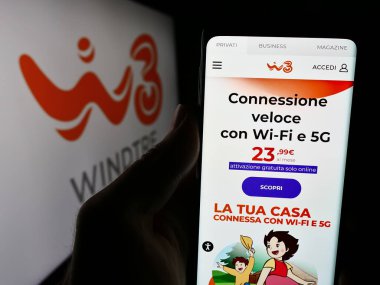 Stuttgart, Almanya - 06-26-2024: Telekomünikasyon şirketi Rüzgâr Tre S.p.A. 'nın (WINDTRE) internet sayfası ile logo önünde cep telefonu tutan kişi. Telefon ekranının merkezine odaklan.