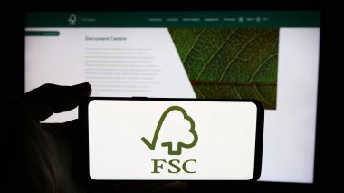 Stuttgart, Almanya - 06-26-2024: İnternet sayfası önünde Forest Stewardship Council GmbH (FSC) örgütünün logosuna sahip cep telefonu sahibi kişi. Telefon ekranına odaklan.