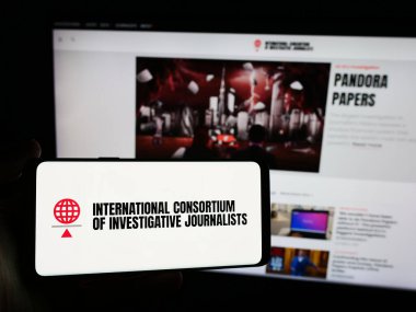 Stuttgart, Almanya - 06-26-2024: İnternet sitesi önünde Uluslararası Araştırmacı Gazeteciler Konsorsiyumu (ICIJ) logosu bulunan kişi. Telefon ekranına odaklan.