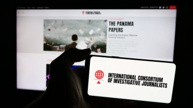 Stuttgart, Almanya - 06-26-2024: İnternet sayfası önünde Uluslararası Araştırmacı Gazeteciler Konsorsiyumu (UAD) logosu bulunan cep telefonu sahibi kişi. Telefon ekranına odaklan.