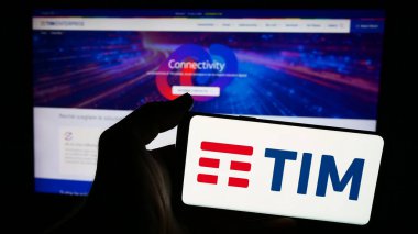 Stuttgart, Almanya - 06-26-2024: İtalyan telekomünikasyon şirketi TIM S.P.A. 'nın logosuna sahip akıllı telefon sahibi kişi web sitesi önünde. Telefon ekranına odaklan.