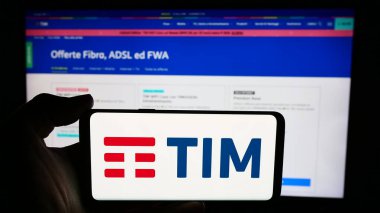 Stuttgart, Almanya - 06-26-2024: İtalyan telekomünikasyon şirketi TIM SpA 'nın logosuyla cep telefonu tutan kişi iş sayfası önünde. Telefon ekranına odaklan.