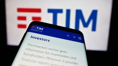 Stuttgart, Almanya - 06-26-2024: İtalyan telekomünikasyon şirketi TIM S.P.A. 'nın web sitesiyle birlikte iş logosu önünde cep telefonu. Telefon ekranının sol üst kısmına odaklan.