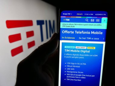 Stuttgart, Almanya - 06-26-2024: İtalyan telekomünikasyon şirketi TIM S.P.A. 'nın internet sayfası ile logo önünde cep telefonu tutan kişi. Telefon ekranının merkezine odaklan.