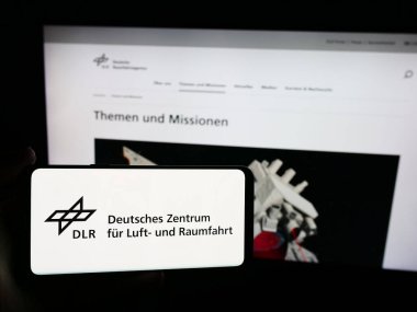 Stuttgart, Almanya - 06-26-2024: Deutsches Zentrum kürk Luft- und Raumfahrt e.V. sitesi ile akıllı telefon (DLR) Logonun önünde. Telefon ekranının sol üst kısmına odaklan.