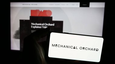 Stuttgart, Almanya - 06-26-2024: Web sitesinin önünde ABD 'li AI yazılım şirketi Mechanical Orchard Inc.' in logosuna sahip akıllı telefon sahibi kişi. Telefon ekranına odaklan.