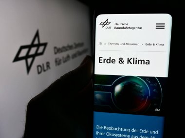 Stuttgart, Almanya - 06-26-2024: Deutsches Zentrum kürk Luft- und Raumfahrt e.V. sitesi ile akıllı telefon (DLR) Logonun önünde. Telefon ekranının sol üst kısmına odaklan.