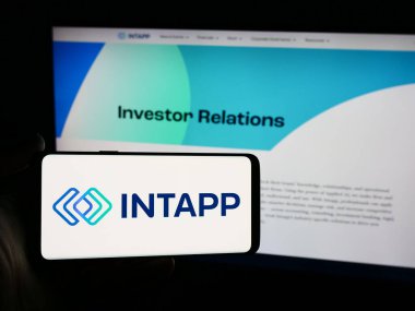 Stuttgart, Almanya - 06-26-2024: Web sayfası önünde üzerinde ABD 'li yazılım şirketi Integration Appliance Inc. (Intapp) logosu bulunan cep telefonu sahibi kişi. Telefon ekranına odaklan.