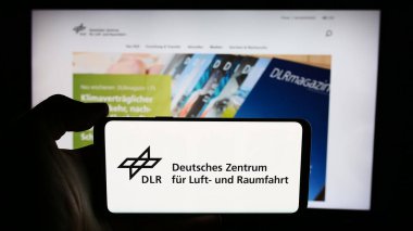 Stuttgart, Almanya - 06-26-2024: Deutsches Zentrum kürk Luft- und Raumfahrt e.V. sitesi ile akıllı telefon (DLR) Logonun önünde. Telefon ekranının sol üst kısmına odaklan.