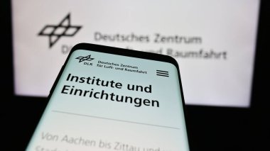 Stuttgart, Almanya - 06-26-2024: Deutsches Zentrum kürk Luft- und Raumfahrt e.V. sitesi ile akıllı telefon (DLR) Logonun önünde. Telefon ekranının sol üst kısmına odaklan.