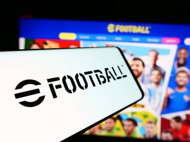 Stuttgart, Almanya - 06-27-2024: İnternet sitesi önünde futbol oyunu eFootball (Konami) logosu olan cep telefonu. Telefon ekranının merkez soluna odaklan.