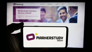 Stuttgart, Almanya - 06-27-2024: İngiliz sigorta şirketi Markerstudy Group Limited 'in logosuna sahip cep telefonu sahibi kişi iş sayfasının önünde. Telefon ekranına odaklan.
