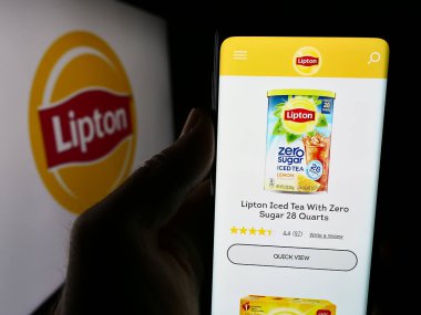Stuttgart, Almanya - 07-03-2024: İş logosu önünde çay markası Lipton 'un web sayfası ile cep telefonu tutan kişi. Telefon ekranının merkezine odaklan.