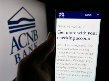 Stuttgart, Almanya - 07-03-2024: ABD 'li finans hizmetleri şirketi ACNB Corporation' ın web sayfası ile logo önünde akıllı telefon tutan kişi. Telefon ekranının merkezine odaklan.