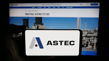 Stuttgart, Almanya - 07-03-2024: ABD 'li ekipman şirketi Astec Industries Inc.' in logosuyla cep telefonu sahibi kişi iş sayfasının önünde. Telefon ekranına odaklan.