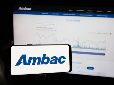 Stuttgart, Almanya - 07-03-2024: İnternet sayfası önünde Amerikan finans şirketi Ambac Financial Group Inc. 'in logosuyla cep telefonu bulunduran kişi. Telefon ekranına odaklan.