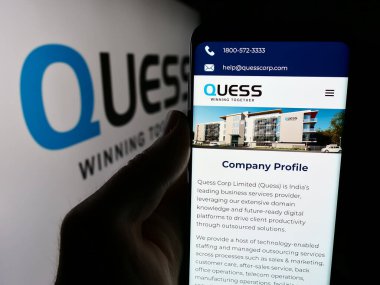 Stuttgart, Almanya - 07-03-2024: Hint iş hizmetleri şirketi Quess Corp Limited 'in logolu web sitesiyle cep telefonu tutan kişi. Telefon ekranının merkezine odaklan.