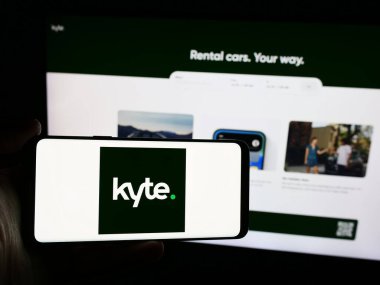 Stuttgart, Almanya - 07-04-2024: İnternet sitesi önünde üzerinde ABD 'li araba kiralama şirketi Kyte Systems Inc.' in logosu bulunan akıllı telefon sahibi kişi. Telefon ekranına odaklan.