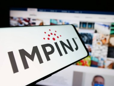 Stuttgart, Almanya - 07-04-2024: Amerikan RFID şirketi Impinj Inc. 'in logosuna sahip cep telefonu. Telefon ekranının soluna odaklan.