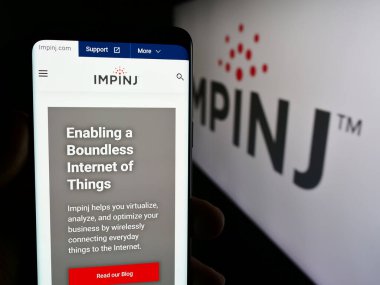 Stuttgart, Almanya - 07-04-2024: İş logosu önünde ABD 'li RFID şirketi Impinj Inc.' in web sayfası ile cep telefonu tutan kişi. Telefon ekranının merkezine odaklan.