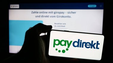 Stuttgart, Almanya - 07-04-2024: Alman ödeme şirketi Paydirekt GmbH 'nin (Giropay) logosuna sahip cep telefonu sahibi kişi iş sayfasının önünde. Telefon ekranına odaklan.