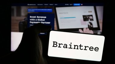 Stuttgart, Almanya - 07-04-2024: İngiliz ödeme şirketi Braintree 'nin (PayPal) logosuna sahip cep telefonu sahibi kişi iş sayfasının önünde. Telefon ekranına odaklan.