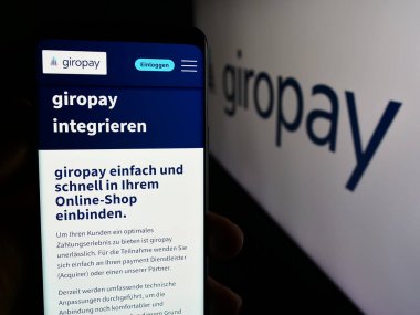 Stuttgart, Almanya - 07-04-2024: Logo önünde Alman ödeme şirketi Giropay 'in (Paydirekt GmbH) web sayfası ile akıllı telefon tutan kişi. Telefon ekranının merkezine odaklan.