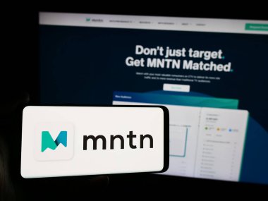 Stuttgart, Almanya - 07-05-2024: İnternet sitesinin önünde ABD 'li reklam yazılım şirketi MNTN Inc.' nin logosuna sahip akıllı telefon sahibi kişi. Telefon ekranına odaklan.