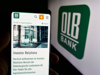 Stuttgart, Almanya - 07-05-2024: Logo önünde Alman Oldenburgische Landesbank AG (OLB) şirketinin web sayfası ile akıllı telefon tutan kişi. Telefon ekranının merkezine odaklan.