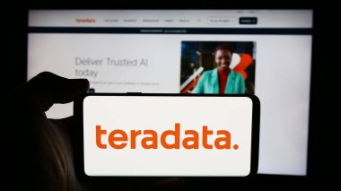 Stuttgart, Almanya - 07-05-2024: ABD veritabanı yazılım şirketi Teradata Corporation 'ın logosuyla cep telefonu sahibi kişi iş sayfası önünde. Telefon ekranına odaklan.