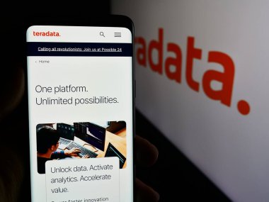 Stuttgart, Almanya - 07-05-2024: ABD veritabanı yazılım şirketi Teradata Corporation 'ın web sayfası ile logo önünde cep telefonu tutan kişi. Telefon ekranının merkezine odaklan.