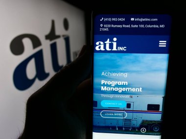 Stuttgart, Almanya - 07-05-2024: ABD özel malzeme şirketi ATI Inc. 'nin web sayfası ile akıllı telefon sahibi kişi iş logosu önünde. Telefon ekranının merkezine odaklan.
