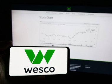 Stuttgart, Almanya - 07-05-2024: İnternet sayfasının önünde Amerikan elektronik şirketi WESCO International Inc. 'in logosuna sahip cep telefonu sahibi kişi. Telefon ekranına odaklan.