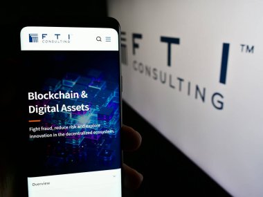 Stuttgart, Almanya - 07-06-2024: ABD 'li iş danışmanlığı şirketi FTI Consulting Inc.' in internet sayfası ile logo önünde cep telefonu tutan kişi. Telefon ekranının merkezine odaklan.