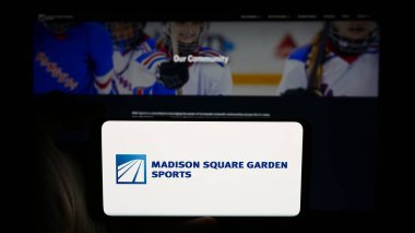 Stuttgart, Almanya - 07-06-2024: ABD 'li Madison Square Garden Sports Corp şirketinin logosunun bulunduğu cep telefonu sahibi kişi iş sayfasının önünde. Telefon ekranına odaklan.