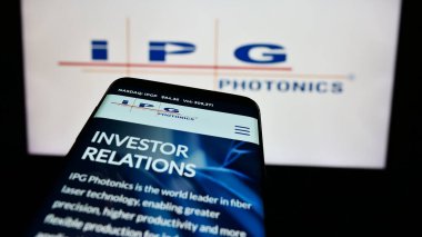 Stuttgart, Germany - 07-06-2024: Mobile phone with webpage of US laser company IPG Photonics Corporation in front of business logo. Focus on top-left of phone display. clipart