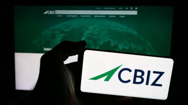 Stuttgart, Almanya - 07-06-2024: İnternet sitesi önünde ABD 'li finans danışmanlık şirketi CBIZ Inc.' in logosuna sahip kişi. Telefon ekranına odaklan.