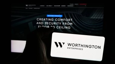 Stuttgart, Almanya - 07-06-2024: İnternet sitesi önünde üzerinde ABD 'li metal işleme şirketi Worthington Enterprises Inc.' in logosu bulunan akıllı telefon sahibi kişi. Telefon ekranına odaklan.